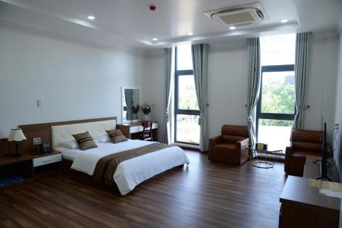 Hoang Hung Hotel في Dĩ An: غرفة نوم بسرير ومكتب وكرسي