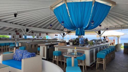 a restaurant with a bar with blue chairs and tables at Xerxis Studios in Nea Roda