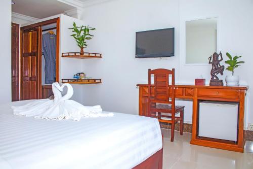 a bedroom with a bed and a desk and a tv at The Blanc Residence in Siem Reap
