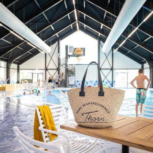 a tote bag sitting on a table in front of a swimming pool at Parc Maasresidence Thorn Apartments in Thorn