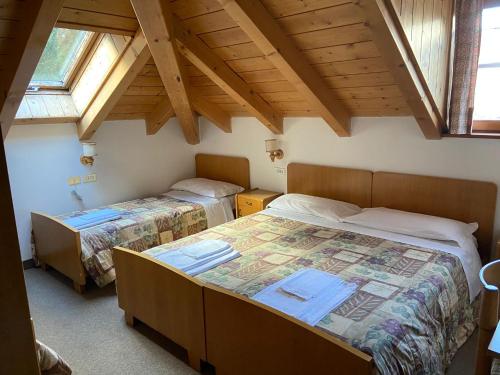duas camas num quarto com duas janelas em Dolomites Hotel La Meridiana em Moena