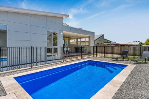 a blue swimming pool in front of a house at Bliss on Sanctuary in Cowes