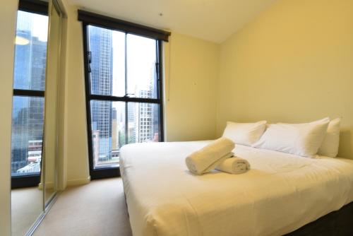een slaapkamer met een wit bed en een groot raam bij Rest Collins Tower collection in Melbourne
