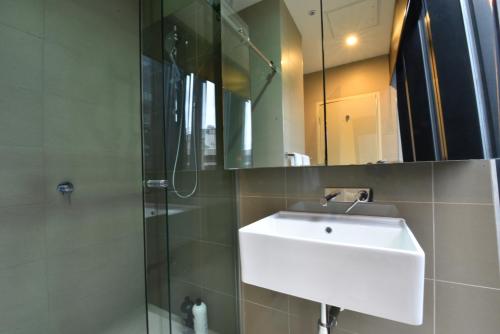 een badkamer met een witte wastafel en een douche bij Rest Collins Tower collection in Melbourne