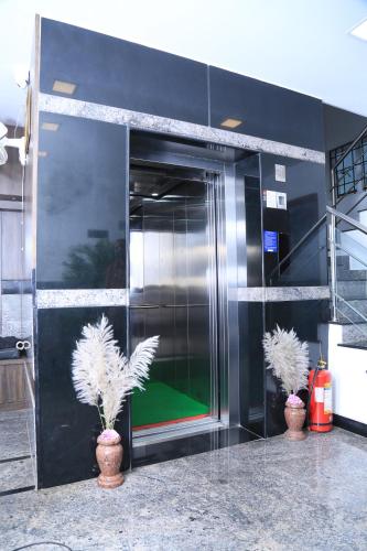 two plants in vases in front of a elevator at CHRISTIAN GUEST HOUSE in Vellore