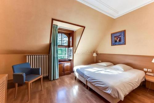 1 dormitorio con 1 cama, 1 silla y 1 ventana en Hotel-Restaurant Domaine de la Grande Garenne, en Neuvy-sur-Barangeon