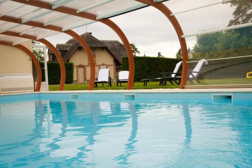 una piscina con pérgola junto a una casa en Hotel-Restaurant Domaine de la Grande Garenne, en Neuvy-sur-Barangeon