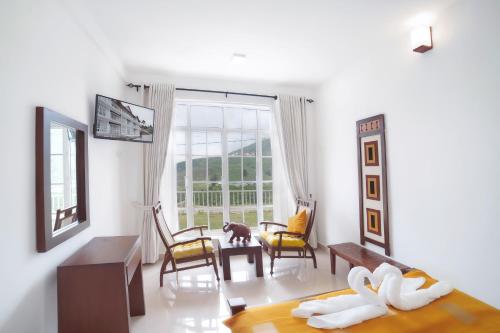 Habitación blanca con cama, mesa y sillas en The Montfort, Nuwaraeliya en Nuwara Eliya
