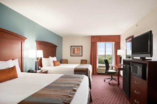 a hotel room with two beds and a flat screen tv at Wingate by Wyndham San Marcos in San Marcos