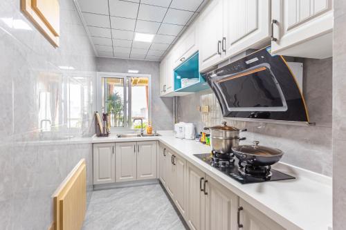 a kitchen with white cabinets and a stove top oven at Cloud & Sea Boutique Apartment in Rizhao