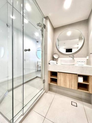 a bathroom with a shower and a sink and a mirror at 18OB - Absolute Beachfront - Noosa Main Beach in Noosa Heads