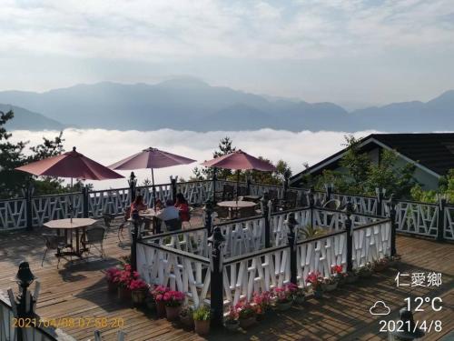 a patio with tables and umbrellas with mountains in the background at Naluwan Villa in Renai