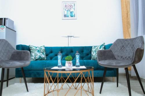 a living room with a blue couch and two chairs at Lux Suites Carina Casey Apartments Bamburi in Bamburi
