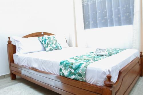 a bed with a wooden frame in a bedroom at Lux Suites Carina Casey Apartments Bamburi in Bamburi