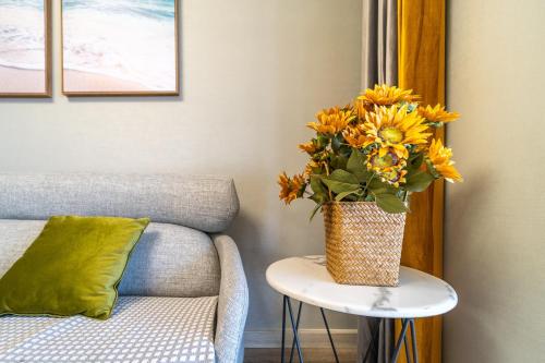 a vase of flowers on a table next to a couch at Cloud & Sea Boutique Apartment in Rizhao