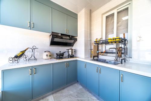 a kitchen with blue cabinets and white counter tops at Cloud & Sea Boutique Apartment in Rizhao
