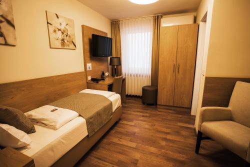 Habitación de hotel con cama y silla en Hotel & Restaurant Rizzelli Superior en Neustadt an der Aisch