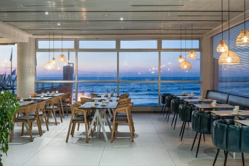 a restaurant with tables and chairs and a large window at Carlton Tel Aviv Hotel – Luxury on the Beach in Tel Aviv