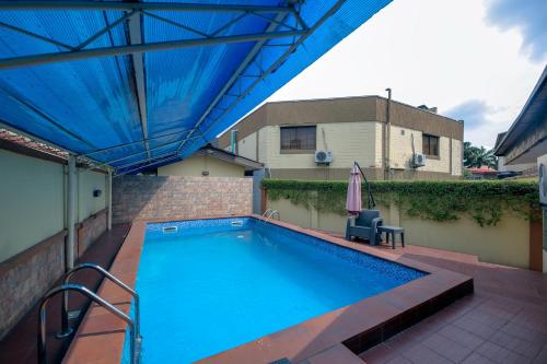 a swimming pool with a blue canopy and an umbrella at KSF Place Alaka in Lagos