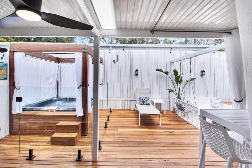 a large deck with a bench and a hot tub at Private Outdoor Spa, Fire Pit - THE RETREAT COOLUM BEACH in Coolum Beach