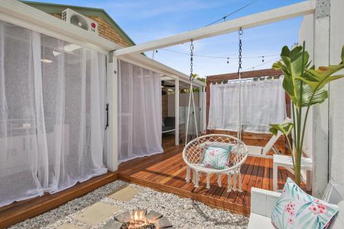 a screened porch with a wicker chair on a deck at Private Outdoor Spa, Fire Pit - THE RETREAT COOLUM BEACH in Coolum Beach