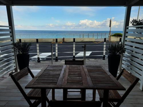 una mesa de madera en un porche con vistas al océano en La casa di SELLY - A Due Metri Dal Mare-, en Bergeggi