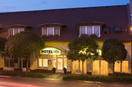 un hotel con una señal de hotel frente a un edificio en Alfa Hotel, en Győr