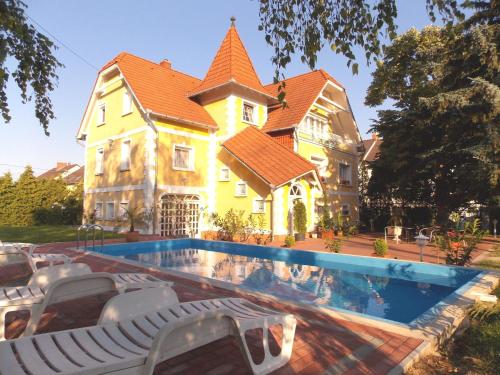 a large house with a swimming pool in front of it at Éden Villa Apartmanház in Balatonfüred