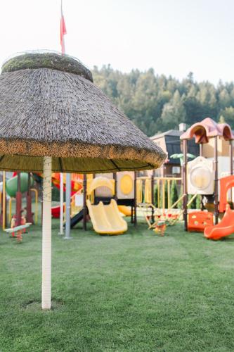 a playground with a straw umbrella in the grass at Villa Monica Apartamenty in Szczyrk