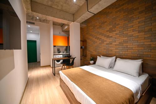 um quarto com uma cama grande e uma parede de tijolos em Rooms Apart-Hotel by RED em Yerevan