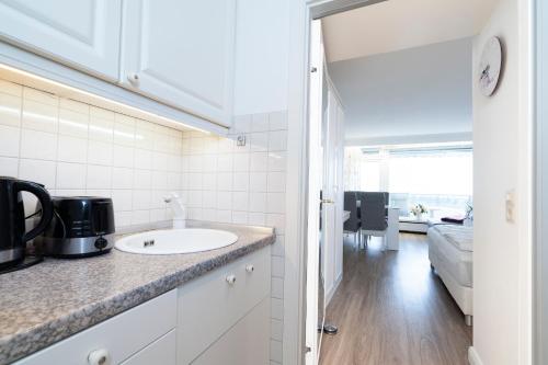 uma cozinha branca com um lavatório e uma sala de estar em Ferienwohnung Landblick App 162 em Timmendorfer Strand