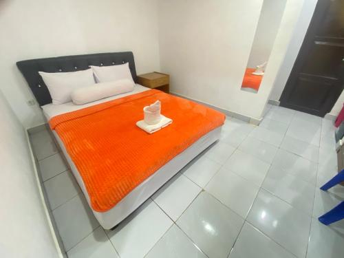 Villa Matano Sorowako 2 Redpartner في Saroako: غرفة نوم مع سرير وبطانية برتقالية
