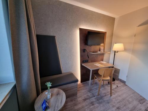 a hotel room with a desk and a chair and a table at Hotel Bavaria Oldenburg in Oldenburg