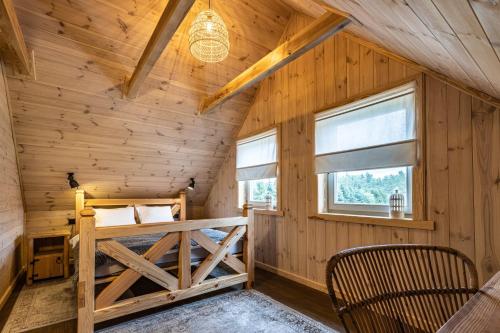 Dormitorio en cabaña de madera con litera y ventana en Apartament w Bukowej Chacie en Mierki