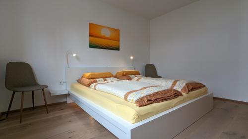 a bedroom with a bed with two chairs and a painting at Gästehaus Freystadt in Freystadt