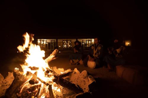 a group of people sitting around a fire at night at Ghazala Camp - Luxury Erg Chigaga Magic in Mhamid