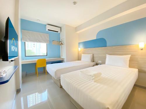 a hotel room with two beds and a desk at Hop Inn Bangkok Krung Thonburi Station in Bangkok