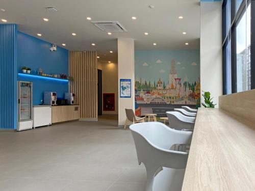 a lobby with white chairs and a blue wall at HOP INN Bangkok Krung Thonburi Station in Bangkok