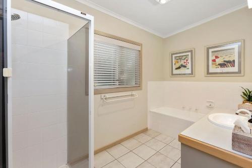 a white bathroom with a shower and a sink at Otway Views in Apollo Bay