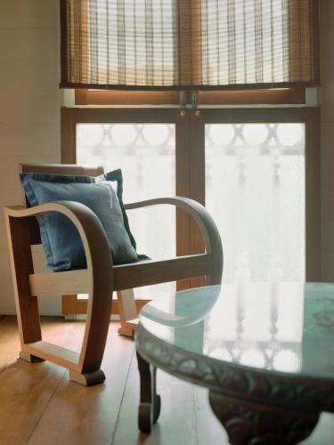 a chair and a glass table in front of a window at neil niwas in Bangkok