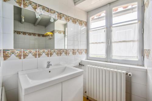 un bagno bianco con lavandino e specchio di Villa spacieuse avec piscine privée, à Salies, 250 m², 6 chbres a Saliès