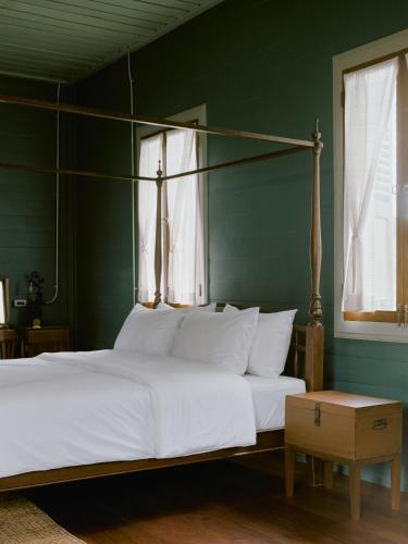 a bedroom with a large white bed and a green wall at neil niwas in Bangkok
