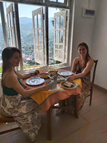 duas mulheres sentadas numa mesa com comida em Holiday Stay Inn em Kandy