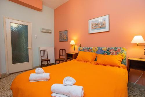 a bedroom with orange walls and a bed with towels at Marina's Bright Getaway - Nafplio Center House in Nafplio