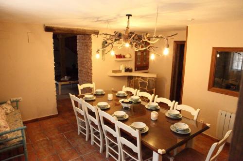 a dining room with a wooden table and white chairs at Mi capricho de Candeleda in Candeleda