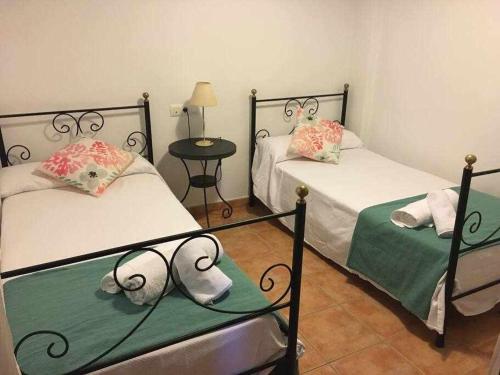 a bedroom with two beds and a table with a lamp at Casa La Rocina Almonte in Almonte