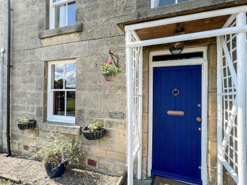 a blue door on the side of a brick house at Blue House Cottage in Elsdon