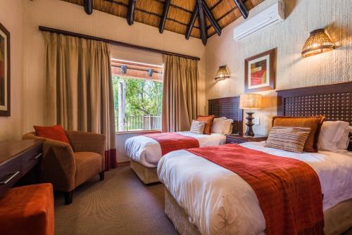 a bedroom with two beds and a chair and a window at Kruger Park Lodge Unit No 521 with Private Pool in Hazyview