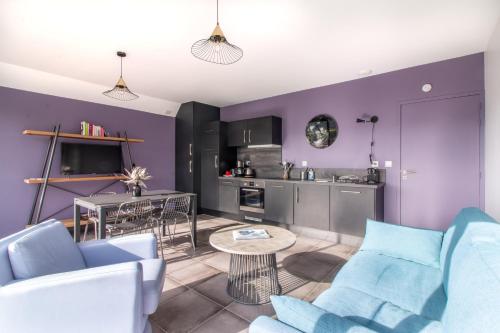 un salon avec un canapé bleu et une cuisine dans l'établissement LE COIN COSY avec Balcon Terrasse parking privé et linge de lit compris, à Sarlat-la-Canéda