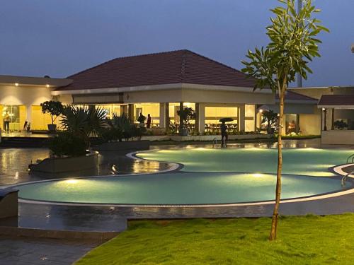 a swimming pool in front of a house at night at Mayur Belgaum Presidency Hotel & Spa in Belgaum